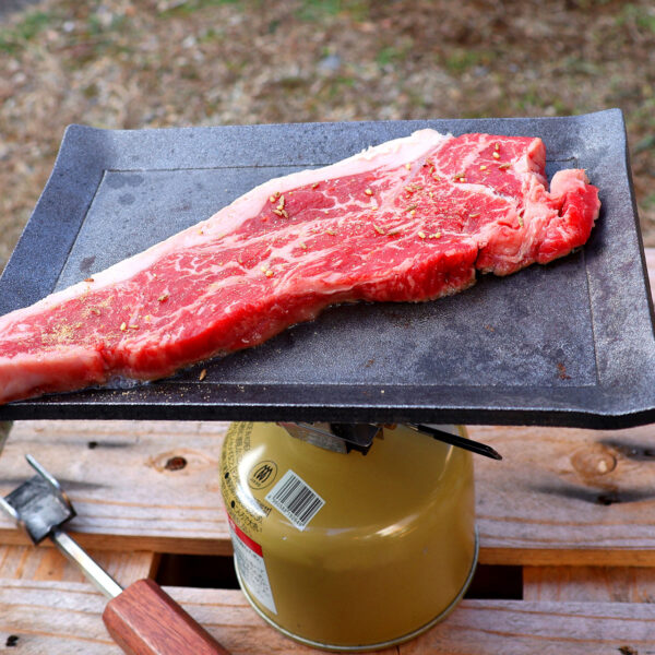 シーズニング不要なアウトドア鉄板にステーキ肉を乗せた写真