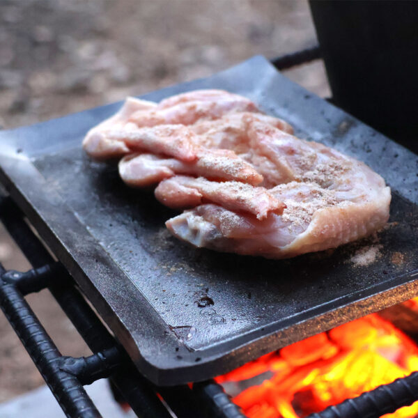 シーズニング不要なアウトドア鉄板で鶏肉を焼いている写真
